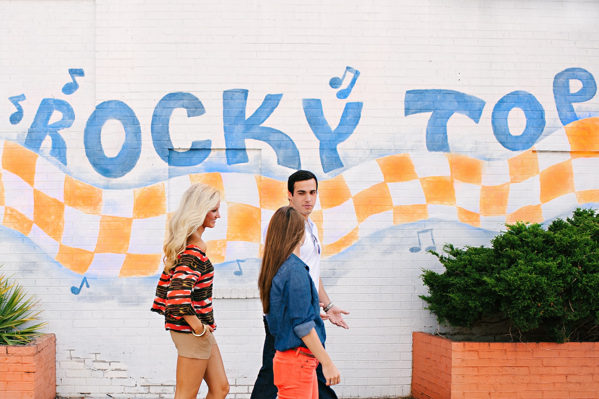 group of people walking in front of a mural that says "Rocky Top"